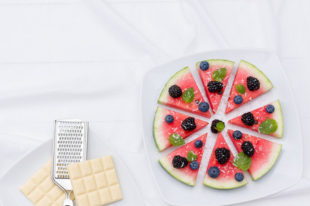 Watermelon pizza slices with fresh blueberry, blackberry, chips of white chocolate and green mint leaves.の写真素材