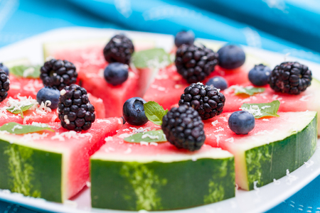 Watermelon pizza slices with fresh blueberry, blackberry, chips of white chocolate and green mint leaves.の写真素材