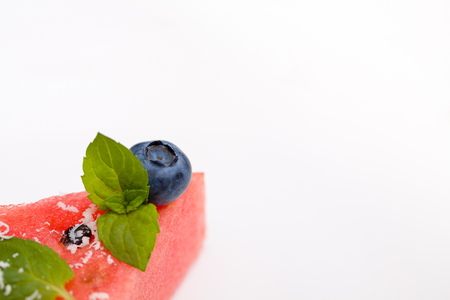 One triangle slice of watermelon pizza with fresh blueberry, blackberry, chips of white chocolate and green mint leaves.の写真素材