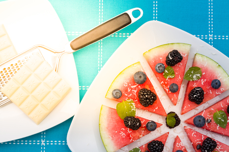 Watermelon pizza slices with fresh blueberry, blackberry, chips of white chocolate and green mint leaves.の写真素材