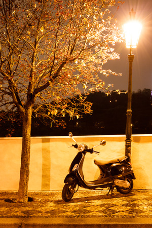 Scooter like Vespa parked under lantern at night.の写真素材