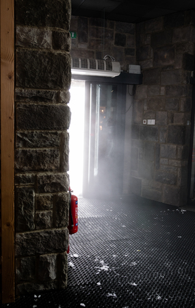 Fire extinguisher hang on the wall, cloud of mist look like smoke, comes through the door.の写真素材