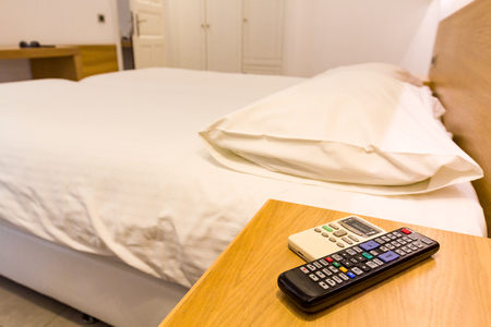 Hotel room with bed and remote tv.の写真素材