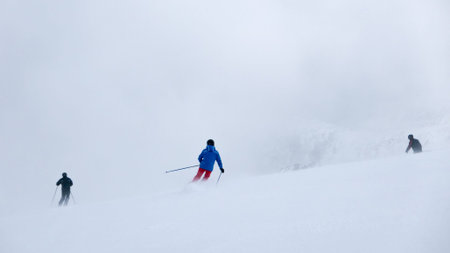 Skiers in thick fog on ski slope in ski resort.の写真素材