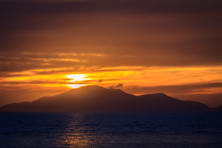 Wonderful sunset behind mountains peak protruding from ocean.の写真素材