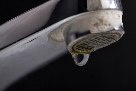 Old leaking faucet with stone and calcium sediments due to hard water.の写真素材