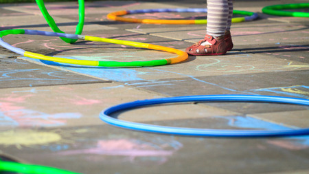 Small girl play hula hoops on playground scratched with chalk.の写真素材