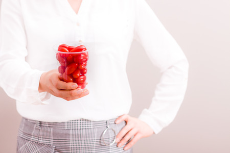 Businesswoman holding cup with fresh cherry tomatoes.の写真素材