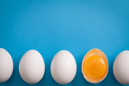 White eggs is laying in row, one of them is bisected and shows yolk. の写真素材