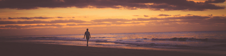 Some person is walking along the beach at sunrise. Banner photography format.の写真素材
