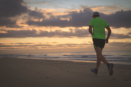 Man is running on the beach at sunrise.の写真素材