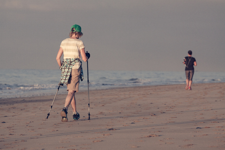 Old woman is workoutting of nordic walking on the beach.の写真素材