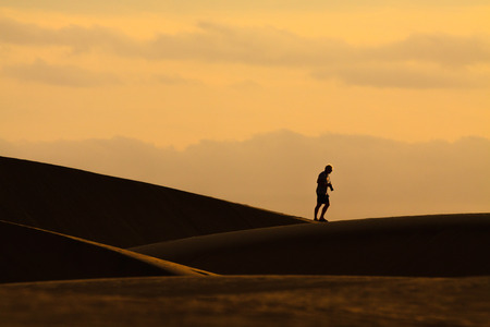 Photographer walking on sand dunes in Maspalomas, Gran Canaria.の写真素材