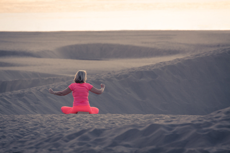 Woman doing yoga (sit) on sand dunes in Maspalomas.の写真素材