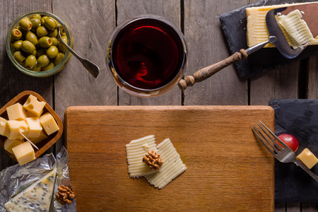 Palette of many types of cheese and some grapes, olives and wine with copy space.の写真素材