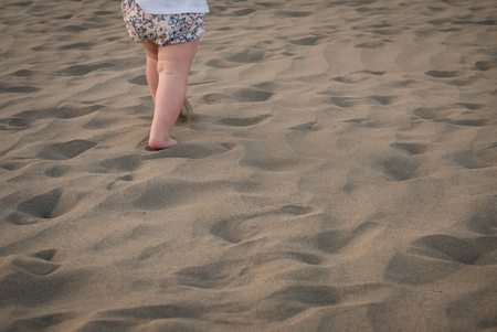 Baby girl is running on sand, view on her legs.の写真素材