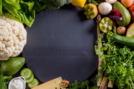 Round black slate with many vegetables around there.の写真素材
