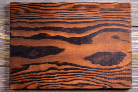 Cutting board from burnt wood. Wooden background.