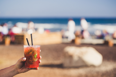 Hand are holding strawberry mojito with sunny coast on background.の写真素材