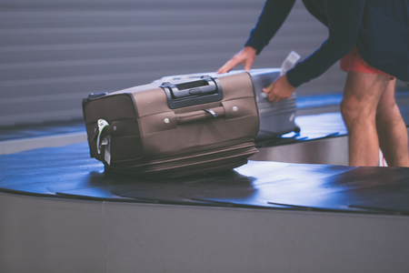 Man takes the luggage on arrival hall from tape conveyor.の写真素材