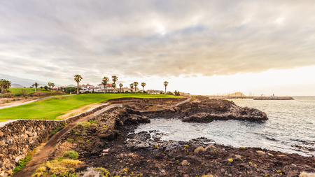 Ground path with handrails and golf course along rocky coastline. Tenerife, Spain.の写真素材