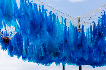 The awareness exhibition on the threat to the marine environment. Plastic bags are hanging on fishing net.の写真素材