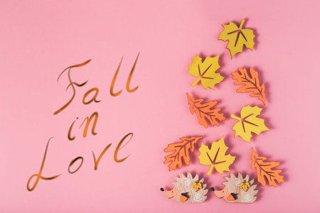 Autumn background with Multicolor wooden figures leaves and hedgehogs and inscription Fall in Love.