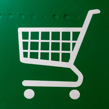 White shopping cart painted sign on green concrete wall.の写真素材