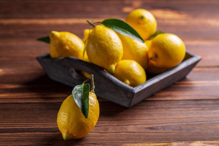 Fresh juicy yellow lemons with leaves on wooden table.の写真素材