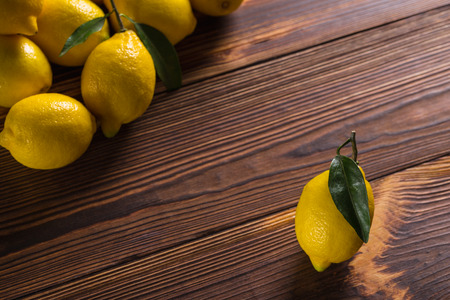 Fresh yellow lemons with leaves lie on a wooden table.の写真素材