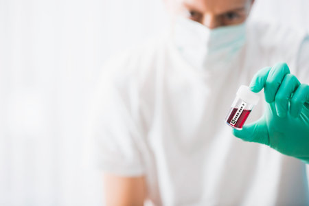 Doctor holds the blood test tube with positive test on coronavirus.