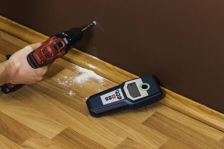 Man hand is scanning wall by cable detector to find a cable before drilling in.の写真素材