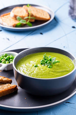 Fresh homemade peas cream soup with mint and toasted bread.の写真素材