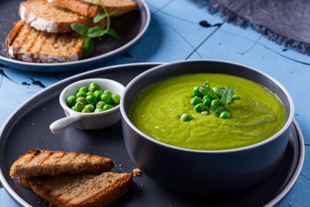 Fresh homemade peas cream soup with mint and toasted bread.の写真素材