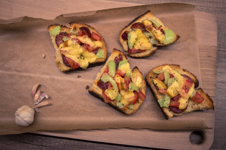 Bruschetta sandwitches with  garlic, cheese, tomatoes and peppers on a brown paper and wood.の写真素材