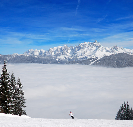 Separate skier on the slopes, riding above the cloudsの写真素材