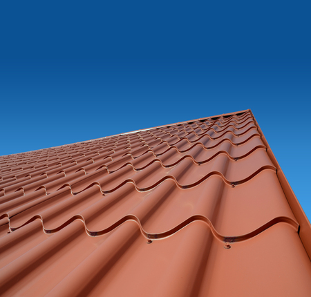 new roof with orange sheet metal and background of blue skyの写真素材