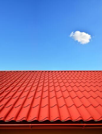 new roof with orange red sheet metal and background of blue skyの写真素材