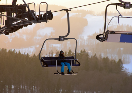 Skiing and snowboarding on the snowy mountains and riding on the chairliftの写真素材