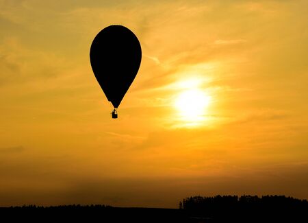 On the background of the sunset, hot air balloons fly and create silhouettesの写真素材