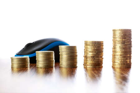 Towers of coins on wooden table in front of mouseの写真素材