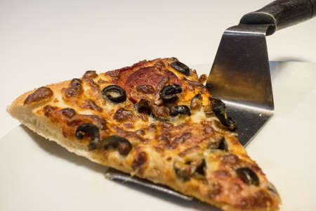Mixed Pizza Slice Serving with Spatula on White Plateの写真素材
