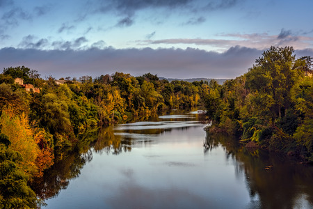 Looking across the Tarn River in Lisle-sur-Tarn under blue skies wirh scattered clouds, Midi-Pyrenees, Franceの写真素材