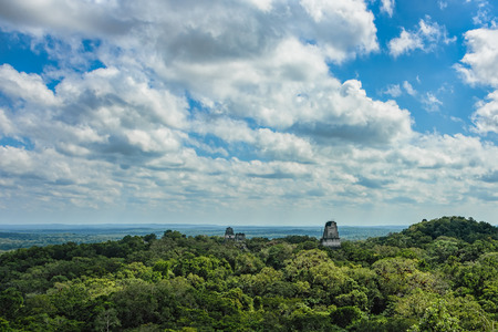Beautiful landscape, temples lost in green forest under blue skies with fluffy white cloudsの写真素材