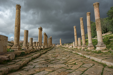 A  collonade street in the ancient city of Gerasa after a storm with dark grey cloudsの写真素材