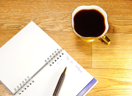Cup of coffee and office notepad on a wooden background