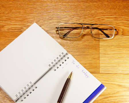 notepad and glasses on a wooden backgroundの写真素材