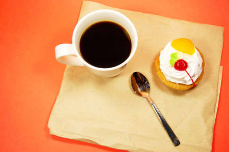 cup of coffee and fruit cake on a paper on a red backgroundの写真素材
