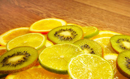Assorted slices of kiwi, lime and orange on a wooden backgroundの写真素材