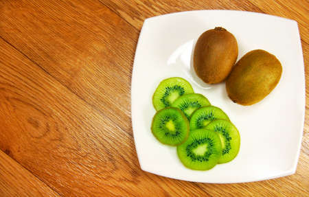 slices of kiwi on a white saucer on a wooden backgroundの写真素材